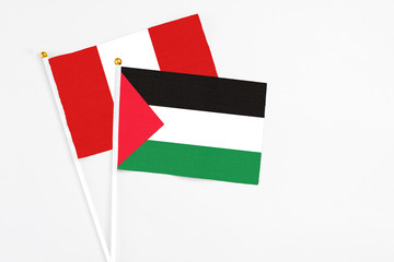 Palestine and Peru stick flags on white background. High quality fabric, miniature national flag. Peaceful global concept.White floor for copy space.