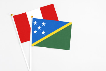 Solomon Islands and Peru stick flags on white background. High quality fabric, miniature national flag. Peaceful global concept.White floor for copy space.