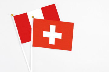 Switzerland and Peru stick flags on white background. High quality fabric, miniature national flag. Peaceful global concept.White floor for copy space.