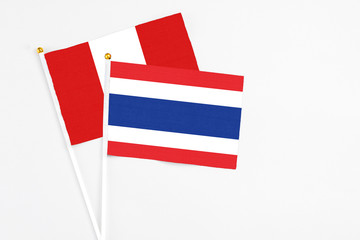 Thailand and Peru stick flags on white background. High quality fabric, miniature national flag. Peaceful global concept.White floor for copy space.