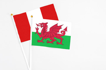 Wales and Peru stick flags on white background. High quality fabric, miniature national flag. Peaceful global concept.White floor for copy space.