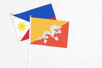 Bhutan and Philippines stick flags on white background. High quality fabric, miniature national flag. Peaceful global concept.White floor for copy space.
