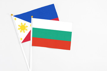 Bulgaria and Philippines stick flags on white background. High quality fabric, miniature national flag. Peaceful global concept.White floor for copy space.