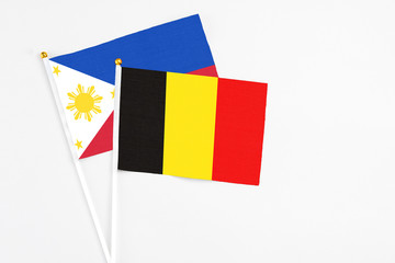 Belgium and Philippines stick flags on white background. High quality fabric, miniature national flag. Peaceful global concept.White floor for copy space.