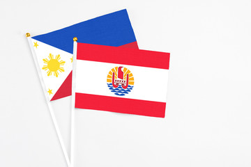 French Polynesia and Philippines stick flags on white background. High quality fabric, miniature national flag. Peaceful global concept.White floor for copy space.