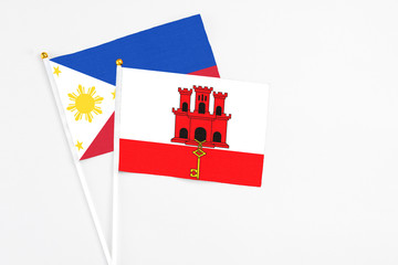 Gibraltar and Philippines stick flags on white background. High quality fabric, miniature national flag. Peaceful global concept.White floor for copy space.
