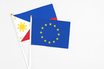 European Union and Philippines stick flags on white background. High quality fabric, miniature national flag. Peaceful global concept.White floor for copy space.
