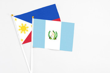 Guatemala and Philippines stick flags on white background. High quality fabric, miniature national flag. Peaceful global concept.White floor for copy space.