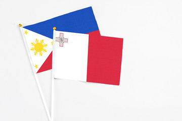 Malta and Philippines stick flags on white background. High quality fabric, miniature national flag. Peaceful global concept.White floor for copy space.