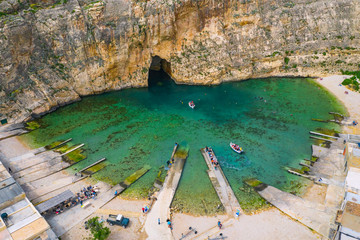 The Inland Sea and two tourist boat. Dwejra is a lagoon of seawater on the island of Gozo. Aerial view of Sea Tunnel near Azure window. Mediterranean sea. Malta country