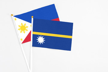 Nauru and Philippines stick flags on white background. High quality fabric, miniature national flag. Peaceful global concept.White floor for copy space.
