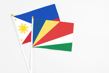 Seychelles and Philippines stick flags on white background. High quality fabric, miniature national flag. Peaceful global concept.White floor for copy space.