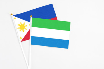Sierra Leone and Philippines stick flags on white background. High quality fabric, miniature national flag. Peaceful global concept.White floor for copy space.