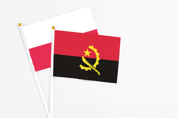 Angola and Poland stick flags on white background. High quality fabric, miniature national flag. Peaceful global concept.White floor for copy space.
