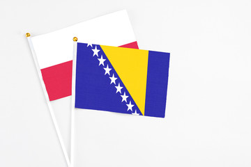 Bosnia Herzegovina and Poland stick flags on white background. High quality fabric, miniature national flag. Peaceful global concept.White floor for copy space.