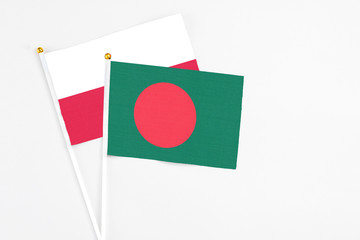 Bangladesh and Poland stick flags on white background. High quality fabric, miniature national flag. Peaceful global concept.White floor for copy space.