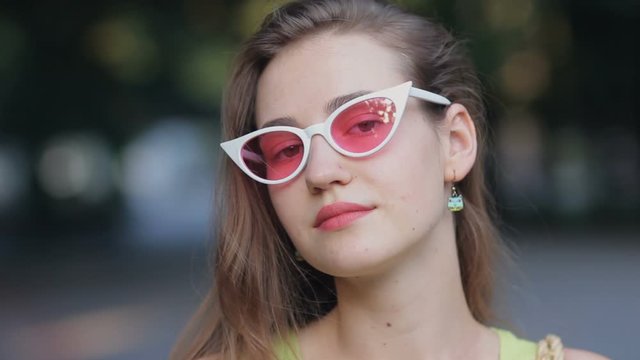 Close up portrait of attractive woman wearing pink sunglasses confident pretty looking at camera
