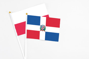 Dominican Republic and Poland stick flags on white background. High quality fabric, miniature national flag. Peaceful global concept.White floor for copy space.