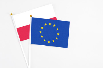 European Union and Poland stick flags on white background. High quality fabric, miniature national flag. Peaceful global concept.White floor for copy space.