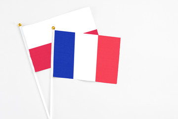 Fototapeta premium France and Poland stick flags on white background. High quality fabric, miniature national flag. Peaceful global concept.White floor for copy space.