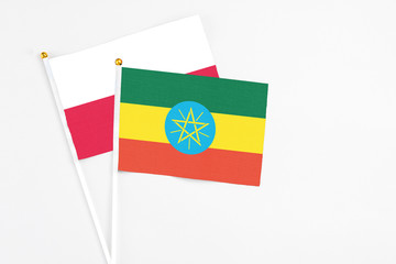 Ethiopia and Poland stick flags on white background. High quality fabric, miniature national flag. Peaceful global concept.White floor for copy space.