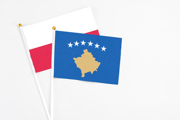 Kosovo and Poland stick flags on white background. High quality fabric, miniature national flag. Peaceful global concept.White floor for copy space.