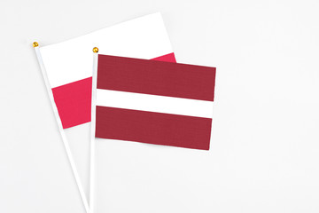 Latvia and Poland stick flags on white background. High quality fabric, miniature national flag. Peaceful global concept.White floor for copy space.