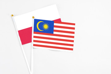 Malaysia and Poland stick flags on white background. High quality fabric, miniature national flag. Peaceful global concept.White floor for copy space.