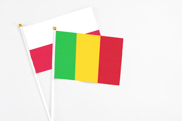 Mali and Poland stick flags on white background. High quality fabric, miniature national flag. Peaceful global concept.White floor for copy space.
