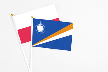 Marshall Islands and Poland stick flags on white background. High quality fabric, miniature national flag. Peaceful global concept.White floor for copy space.
