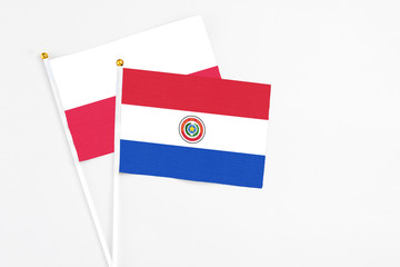 Paraguay and Poland stick flags on white background. High quality fabric, miniature national flag. Peaceful global concept.White floor for copy space.