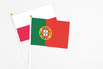 Portugal and Poland stick flags on white background. High quality fabric, miniature national flag. Peaceful global concept.White floor for copy space.