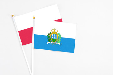 San Marino and Poland stick flags on white background. High quality fabric, miniature national flag. Peaceful global concept.White floor for copy space.