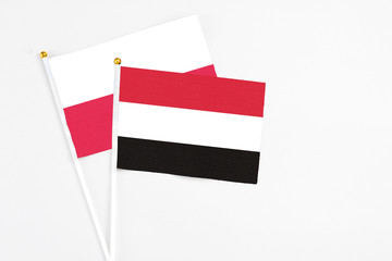 Yemen and Poland stick flags on white background. High quality fabric, miniature national flag. Peaceful global concept.White floor for copy space.