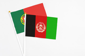 Afghanistan and Portugal stick flags on white background. High quality fabric, miniature national flag. Peaceful global concept.White floor for copy space.