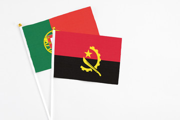 Angola and Portugal stick flags on white background. High quality fabric, miniature national flag. Peaceful global concept.White floor for copy space.