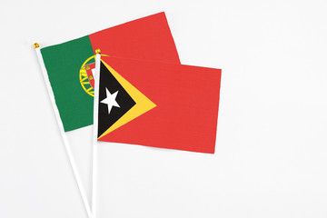 East Timor and Portugal stick flags on white background. High quality fabric, miniature national flag. Peaceful global concept.White floor for copy space.