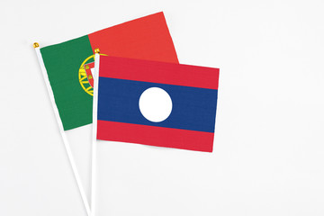 Laos and Portugal stick flags on white background. High quality fabric, miniature national flag. Peaceful global concept.White floor for copy space.