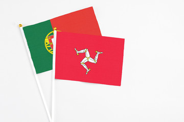 Isle Of Man and Portugal stick flags on white background. High quality fabric, miniature national flag. Peaceful global concept.White floor for copy space.