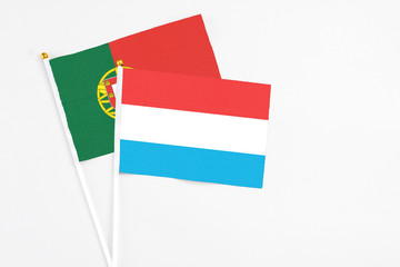 Luxembourg and Portugal stick flags on white background. High quality fabric, miniature national flag. Peaceful global concept.White floor for copy space.