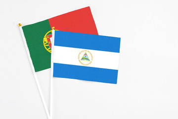 Nicaragua and Portugal stick flags on white background. High quality fabric, miniature national flag. Peaceful global concept.White floor for copy space.