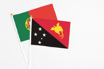 Papua New Guinea and Portugal stick flags on white background. High quality fabric, miniature national flag. Peaceful global concept.White floor for copy space.