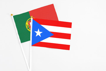 Fototapeta premium Puerto Rico and Portugal stick flags on white background. High quality fabric, miniature national flag. Peaceful global concept.White floor for copy space.