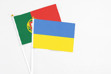 Ukraine and Portugal stick flags on white background. High quality fabric, miniature national flag. Peaceful global concept.White floor for copy space.