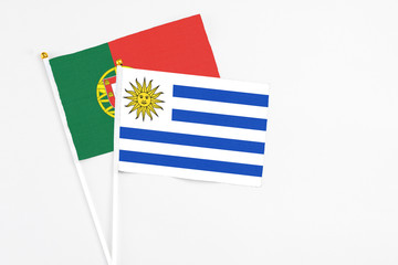 Uruguay and Portugal stick flags on white background. High quality fabric, miniature national flag. Peaceful global concept.White floor for copy space.