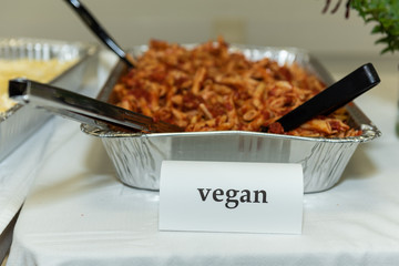 Placard on buffet table indicates that no meat is inside the shrouded serving dish of vegan food.