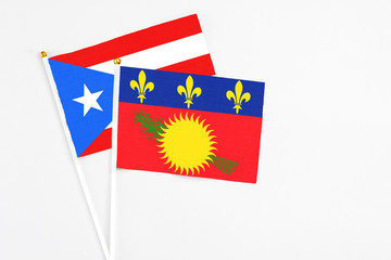 Guadeloupe and Puerto Rico stick flags on white background. High quality fabric, miniature national flag. Peaceful global concept.White floor for copy space.
