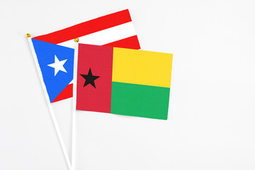 Guinea Bissau and Puerto Rico stick flags on white background. High quality fabric, miniature national flag. Peaceful global concept.White floor for copy space.