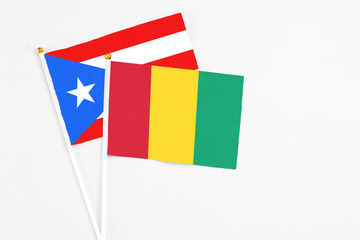 Guinea and Puerto Rico stick flags on white background. High quality fabric, miniature national flag. Peaceful global concept.White floor for copy space.