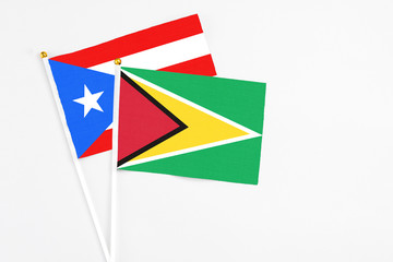 Guyana and Puerto Rico stick flags on white background. High quality fabric, miniature national flag. Peaceful global concept.White floor for copy space.